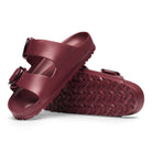 Maroon sandals with a textured sole on a white background