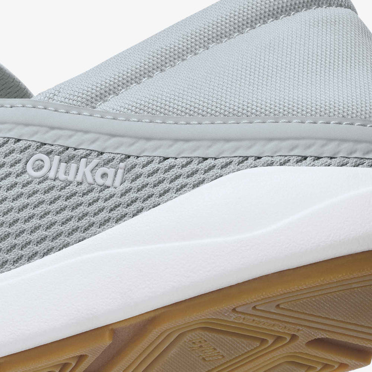 Close-up of a gray shoe with white sole and brown sole tread, featuring the Olukai brand.