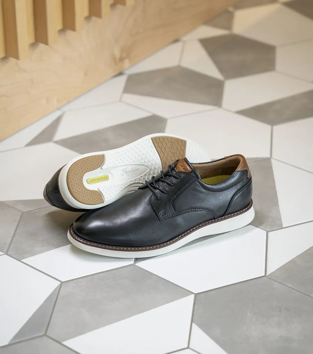 Two pairs of shoes on a geometric-patterned floor.