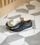 Two pairs of shoes on a geometric-patterned floor.