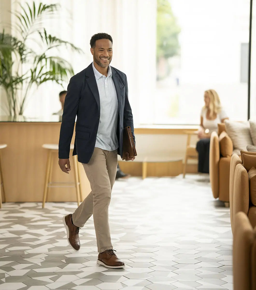 Man walking in a modern office setting with plants and furniture.