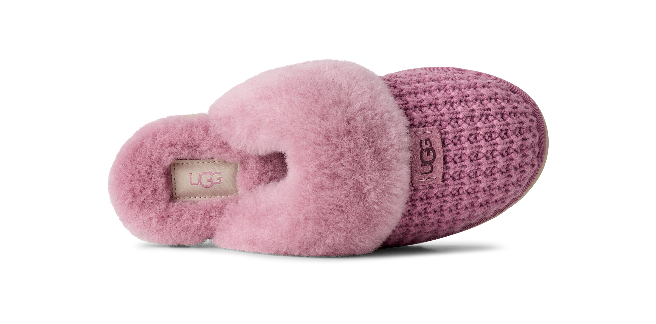 A single UGG slipper shown from the side on a white background, featuring a pink fuzzy shearling collar, a textured knit upper in a dusty mauve-pink, and a beige UGG logo patch on the heel.