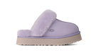 A single UGG slip-on mule slipper in light lavender purple, featuring a soft fuzzy shearling collar and a thick beige platform sole, shown against a plain white background.
