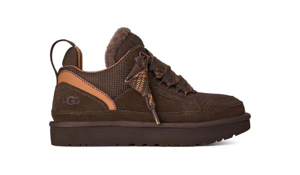 A dark brown UGG lace-up sneaker with a textured mesh upper, suede overlays, a tan leather heel accent, and a thick dark brown sole, shown against a plain white background.