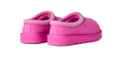 A pair of UGG slip-on slippers in a vibrant pink color, featuring a textured knit trim around the collar and a plush pink interior, shown from a three-quarters angle on a white background.
