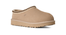 Beige UGG slipper with brown trim on a white background