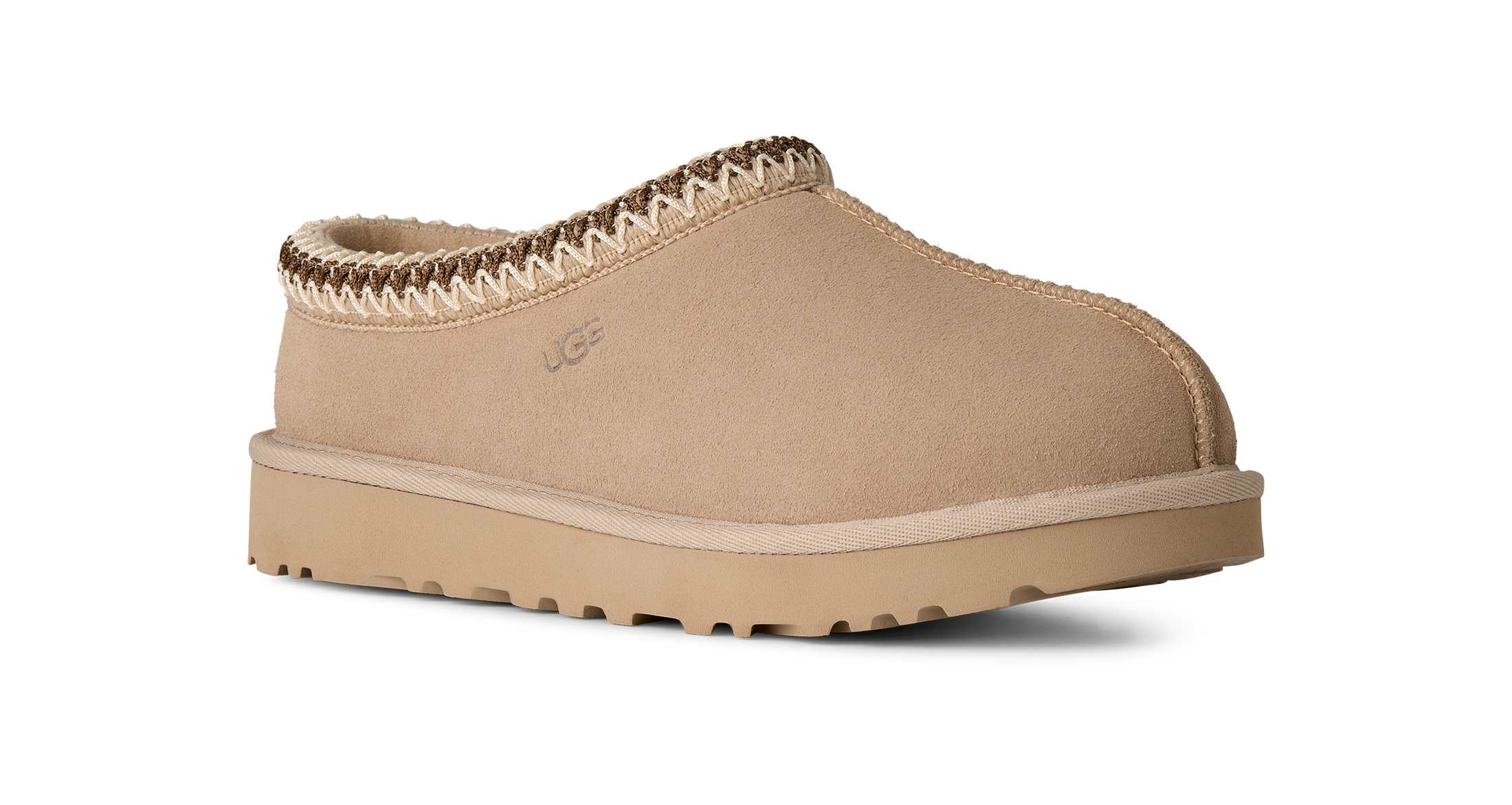 Beige UGG slipper with brown trim on a white background