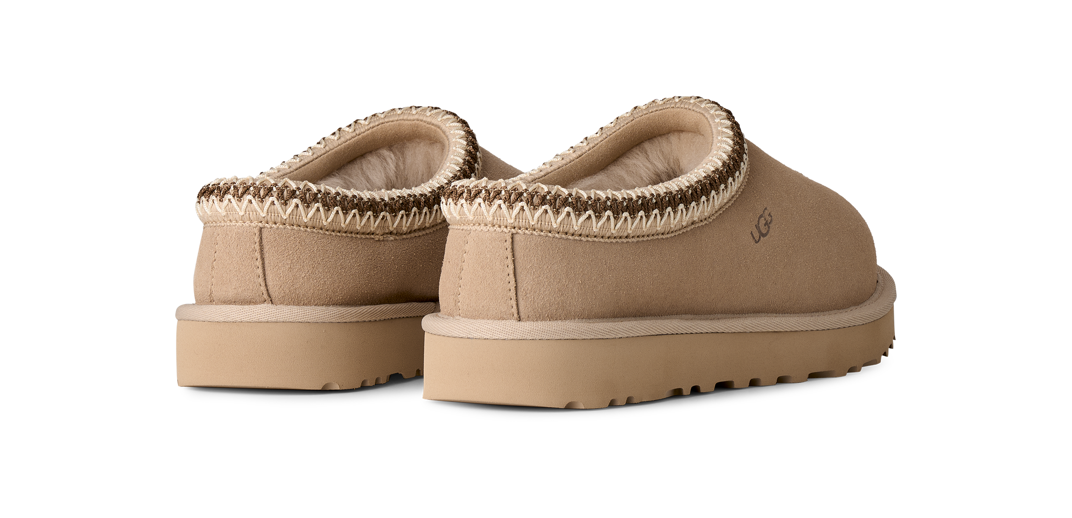 Pair of tan slippers with brown trim on a white background