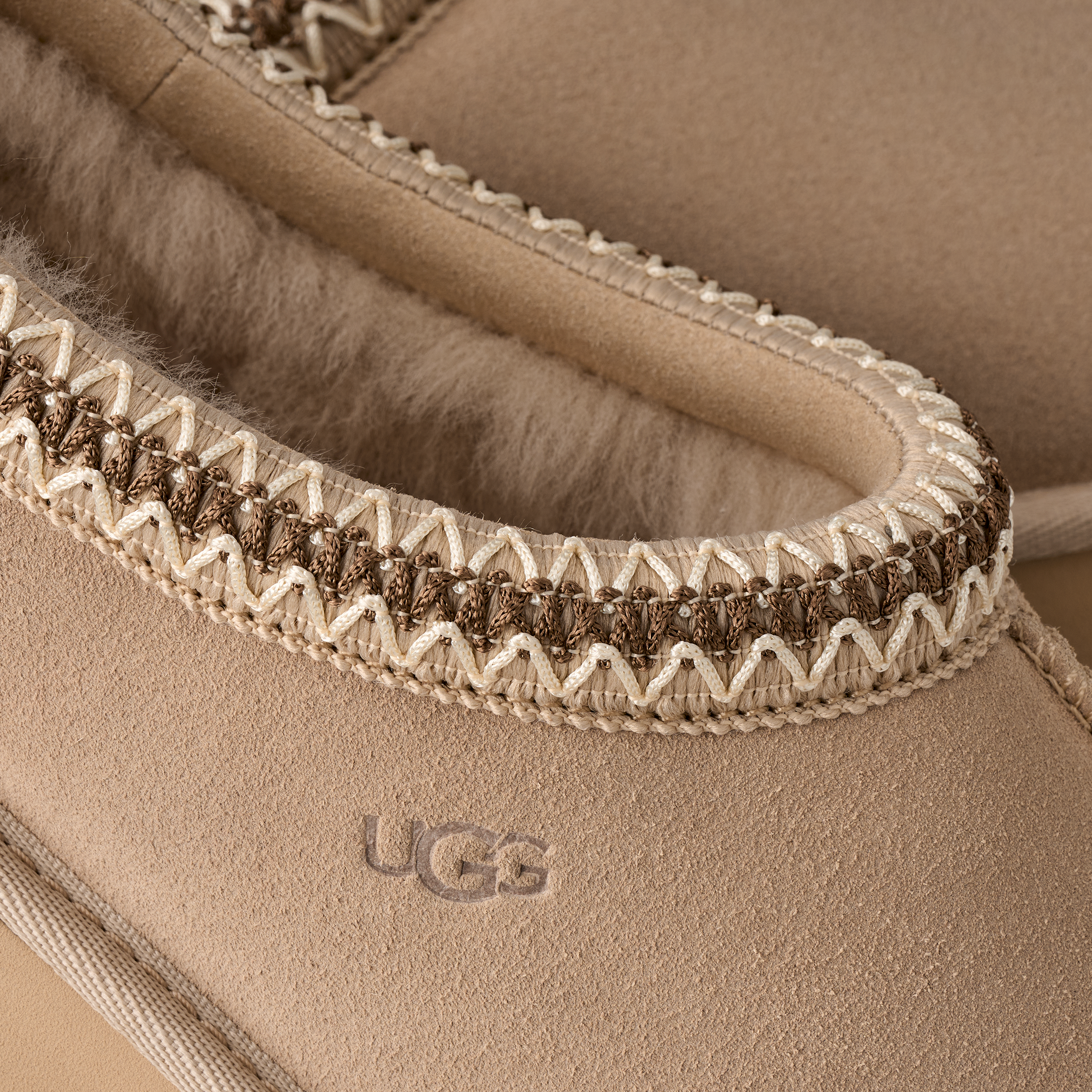 Close-up of a UGG slipper with textured trim and visible brand logo.