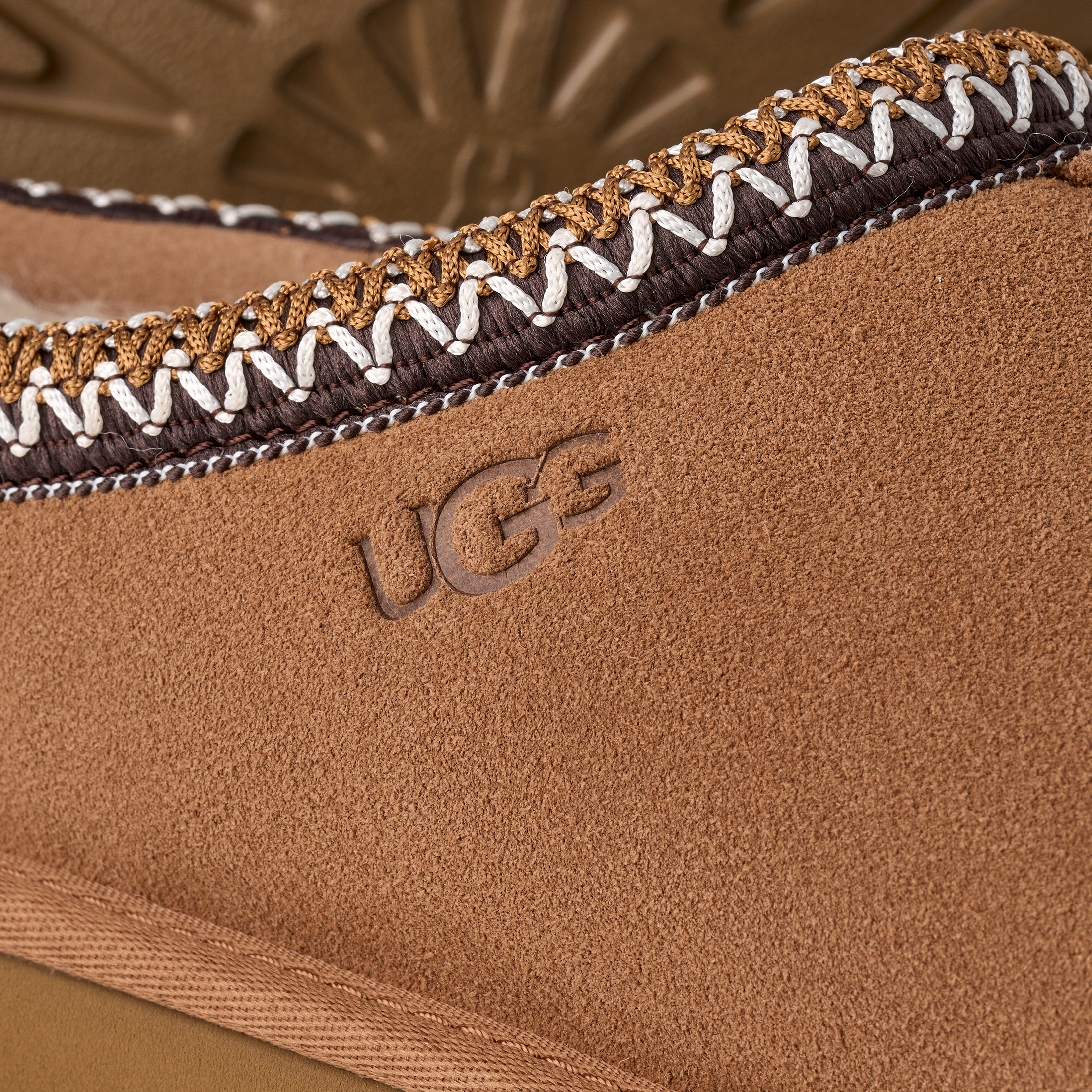 Close-up of a brown UGG boot with decorative stitching detail.