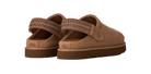 A pair of UGG slip-on clogs in a warm brown suede-like material, featuring a patterned woven strap and a thick brown sole, shown against a solid white background.