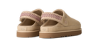 A pair of beige UGG slip-on clogs with a patterned mauve-pink woven strap and brown soles, shown from a three-quarters angle on a white background.