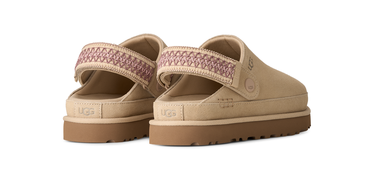 A pair of beige UGG slip-on clogs with a patterned mauve-pink woven strap and brown soles, shown from a three-quarters angle on a white background.