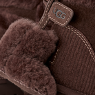 Close-up of a brown UGG boot with fuzzy cuff and brand logo.