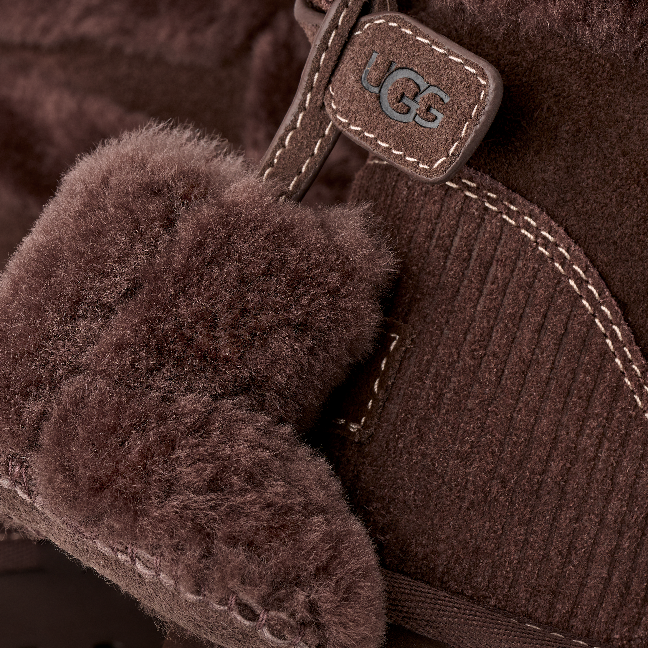 Close-up of a brown UGG boot with fuzzy cuff and brand logo.