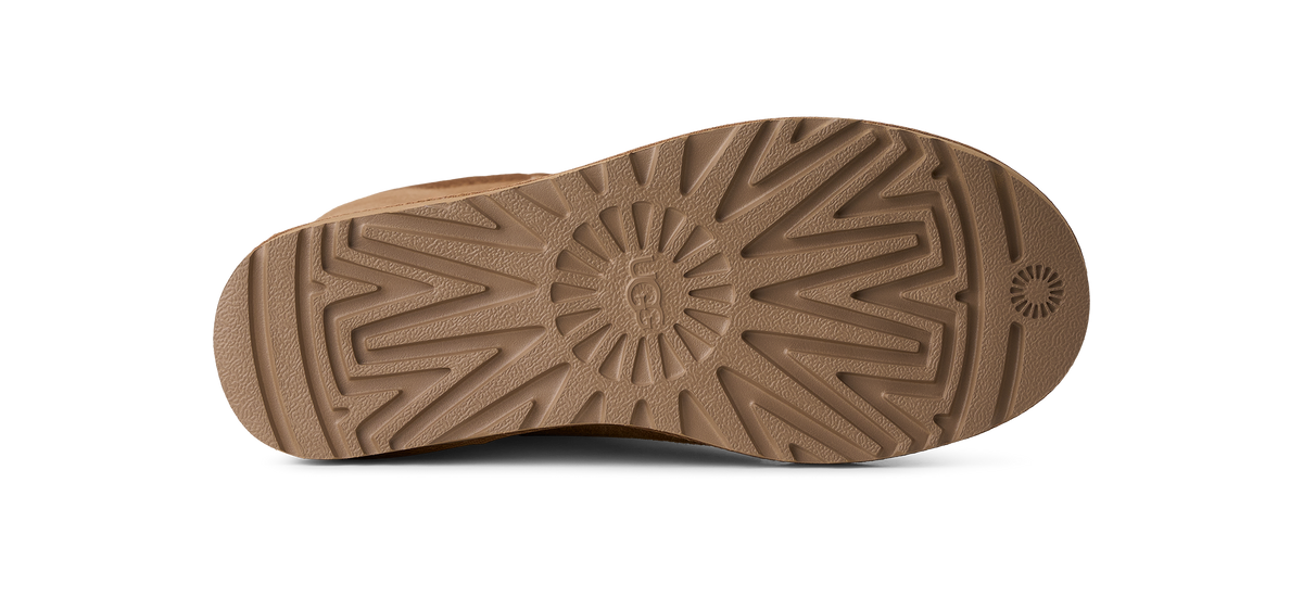 The bottom sole of a brown shoe, showing a detailed tread pattern and a circular logo embossed in the center, isolated on a white background.
