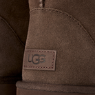 Close-up of a brown suede UGG boot showing the stitched UGG logo patch on the side.