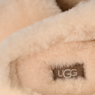 Close-up of beige UGG sheepskin with a visible brand logo.
