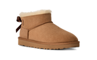 Tan suede boot with white fur lining and brown bow on a white background