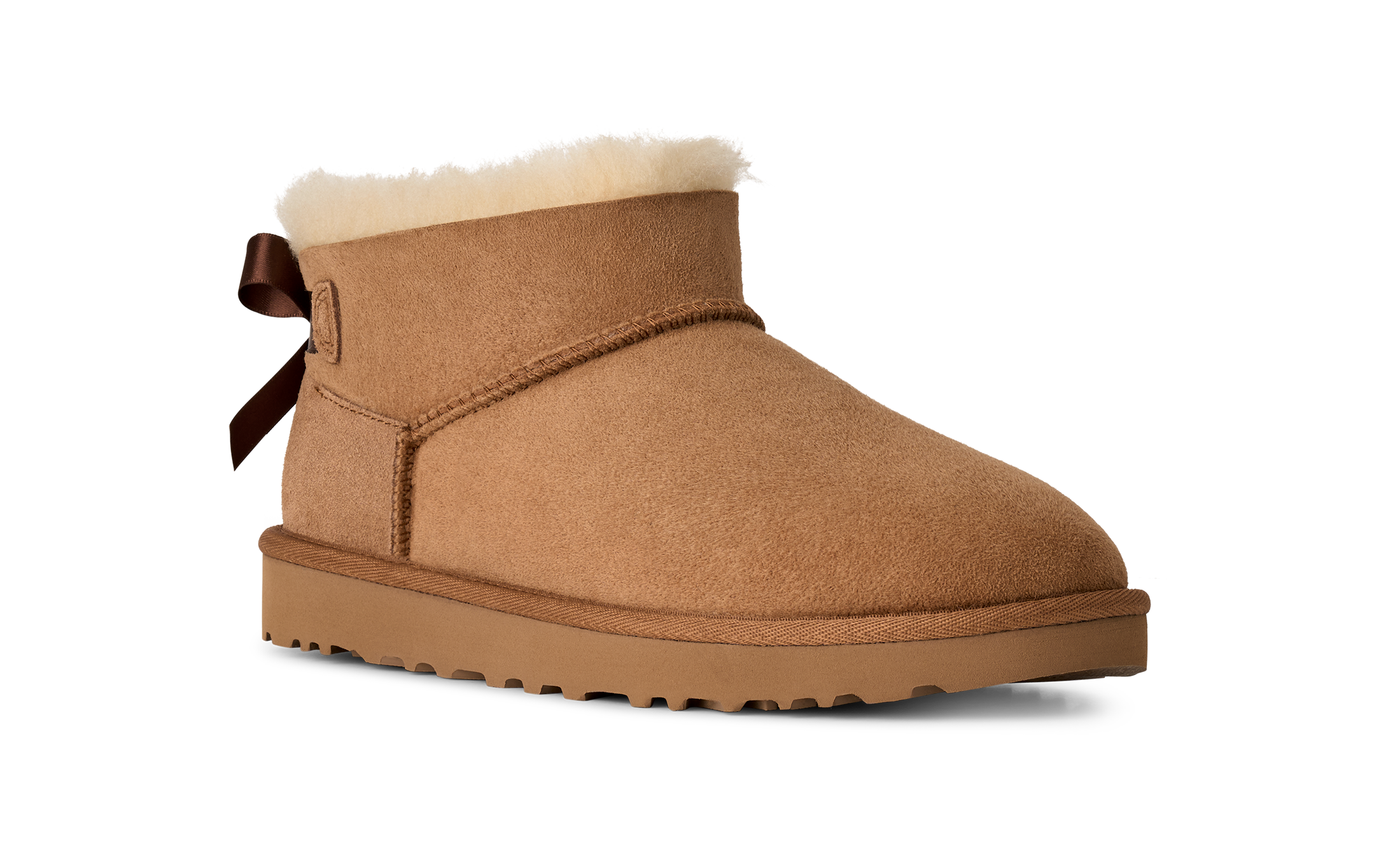 Tan suede boot with white fur lining and brown bow on a white background