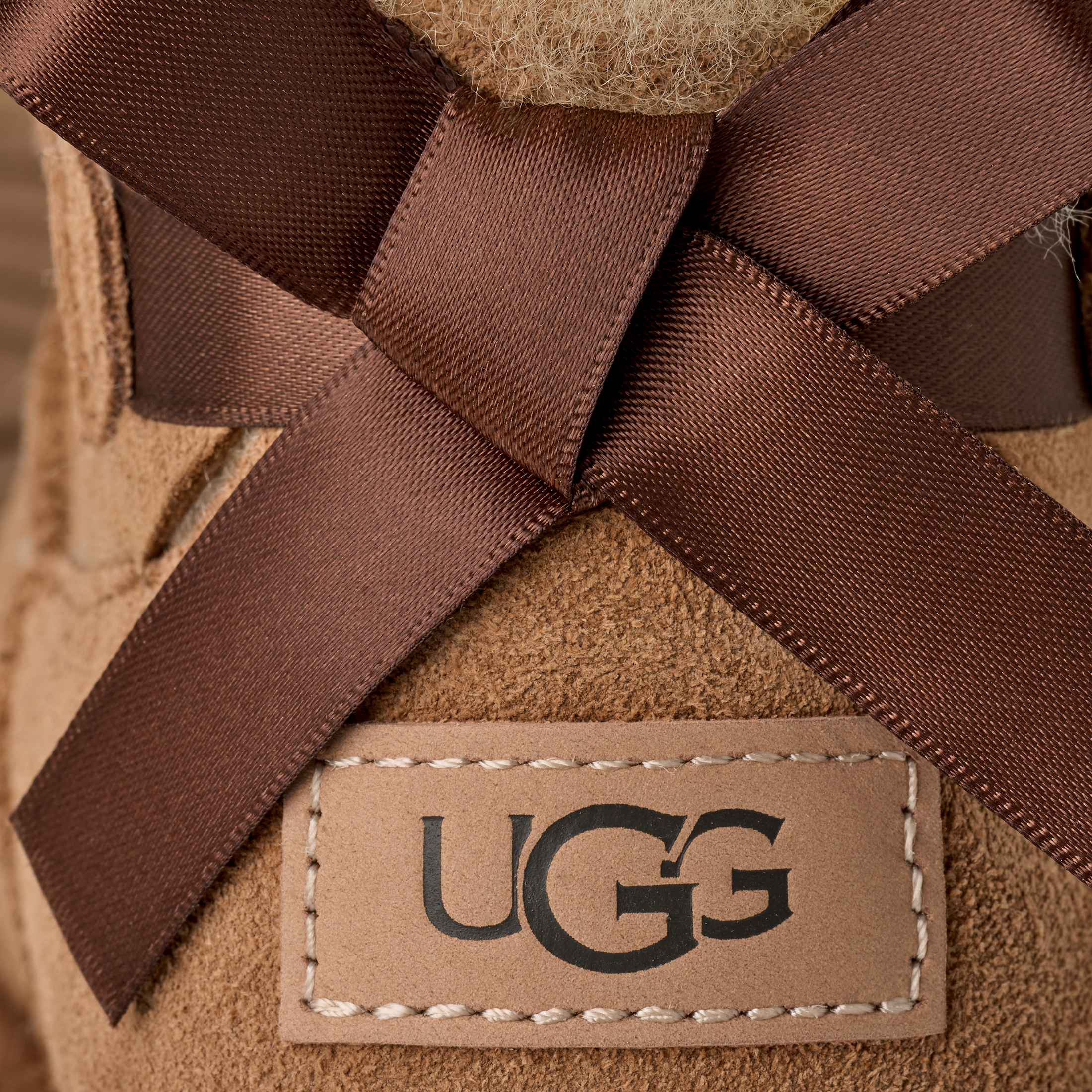 Close-up of a UGG boot with brown laces and visible brand logo.