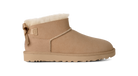 A single beige suede ankle boot with a white shearling lining, a decorative side bow, and a thick lug sole, shown in profile against a white background.