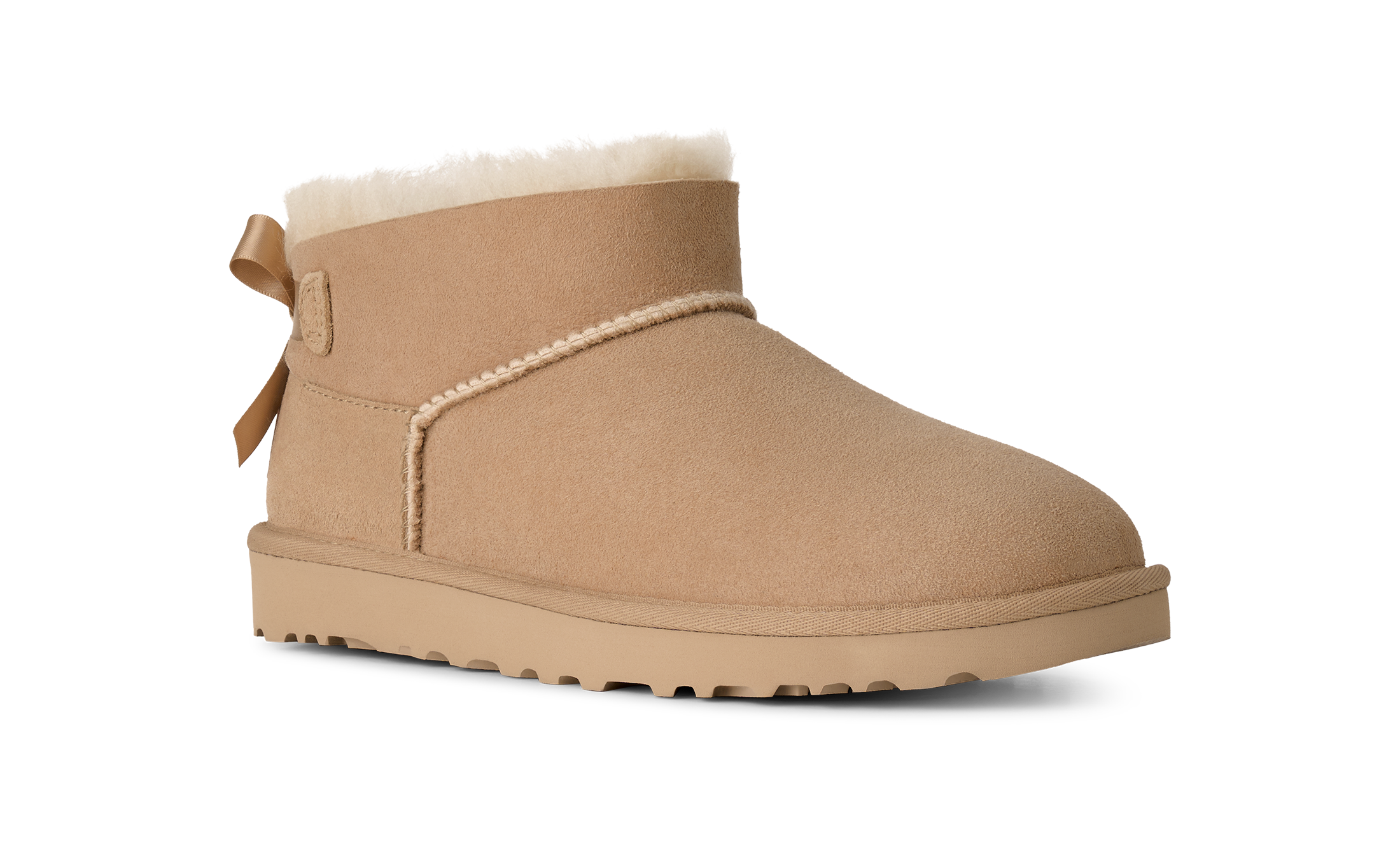 A single tan suede ankle boot with a white shearling lining, a decorative side bow, and a thick lug sole, shown on a plain white background.