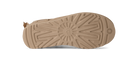 The tan rubber outsole of a boot, showing a detailed tread pattern and a small pull tab on the heel, isolated on a white background.