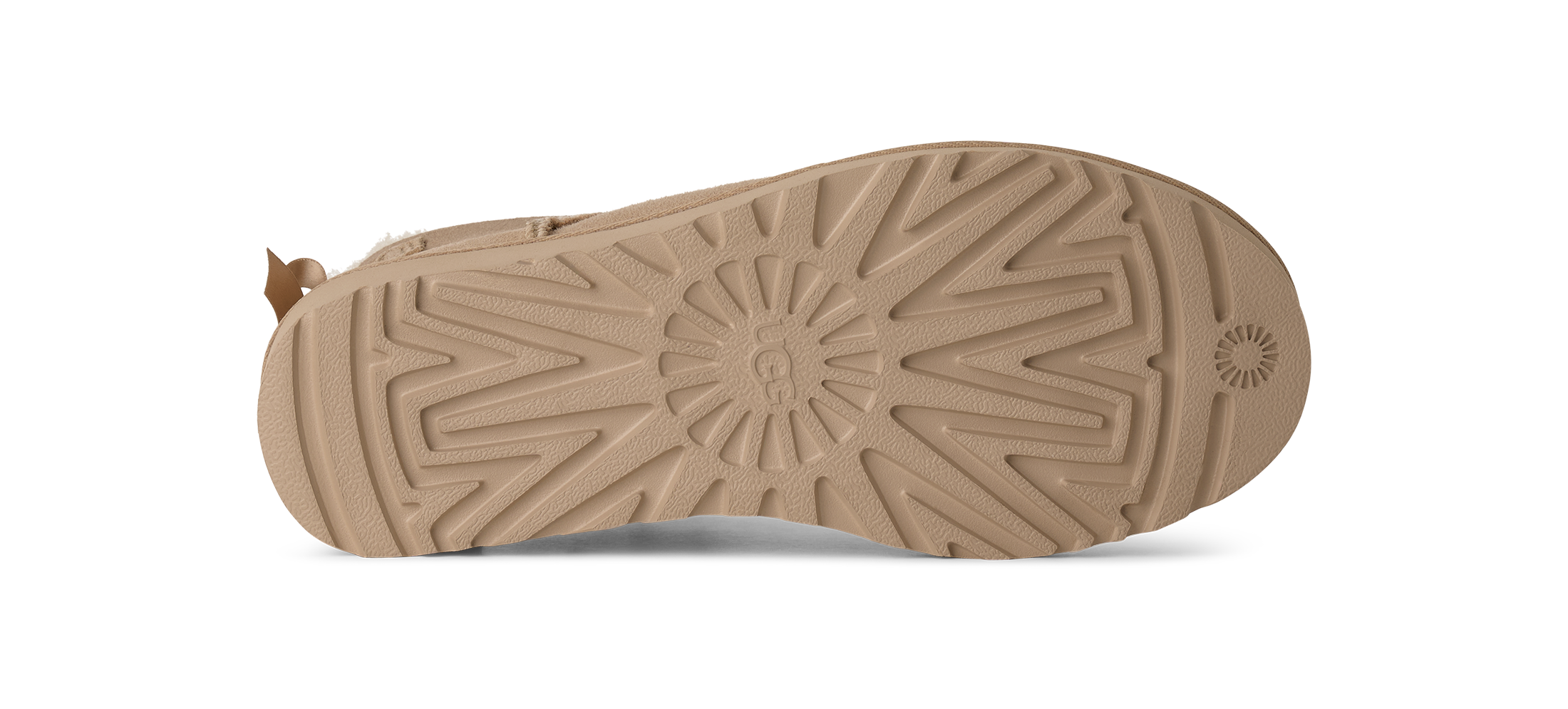 The tan rubber outsole of a boot, showing a detailed tread pattern and a small pull tab on the heel, isolated on a white background.
