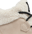 Close-up of a beige suede boot with a thick cream sherpa fleece collar and black laces on a white background.