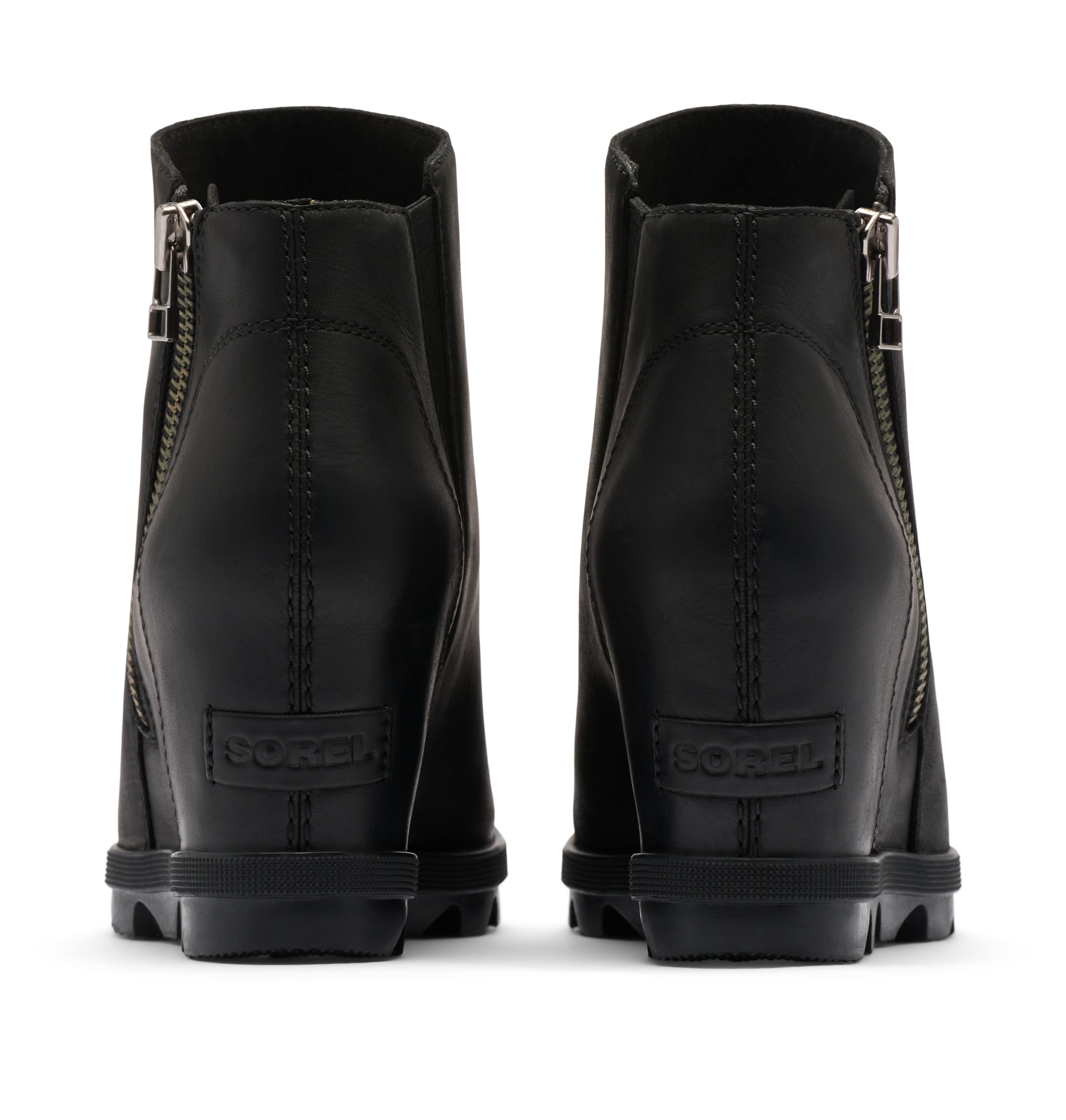 A pair of black leather ankle boots shown from the back, featuring side zippers, a stacked lug sole, and a debossed SOREN logo on the heel.