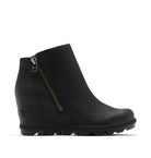 A black leather ankle boot with a side zipper, wedge heel, and chunky lug sole, shown from a side profile on a light beige background.