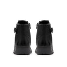 A pair of black ankle boots shown from the back, featuring side buckle straps and thick black soles, set against a plain white background.