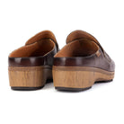 A pair of dark brown leather clogs with chunky, textured natural wood wedge soles, shown from a rear three-quarter angle on a white background.