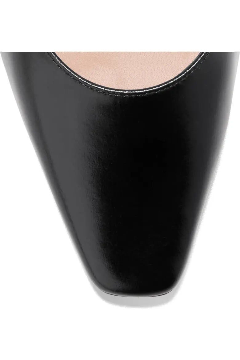 Close-up of a black patent leather pointed-toe shoe with a low-cut vamp, shown against a plain white background.