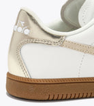 Close-up of a white and beige sneaker with a brand logo on the side.