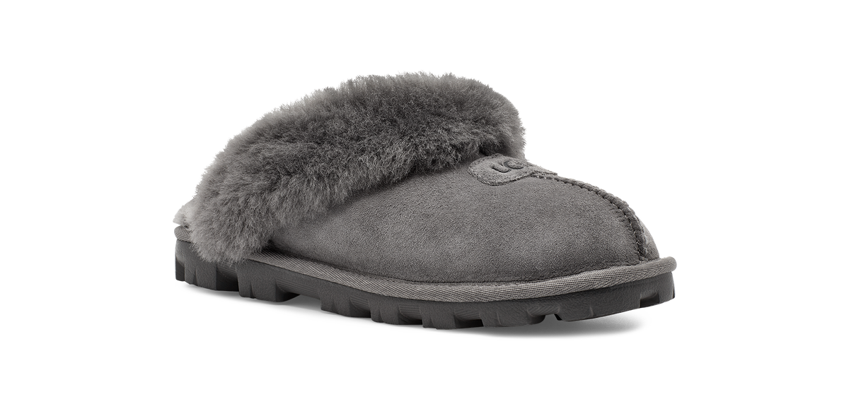 A single gray suede slipper with a thick, fluffy gray faux-fur trim across the top and a rugged black sole, shown from a side profile on a white background.
