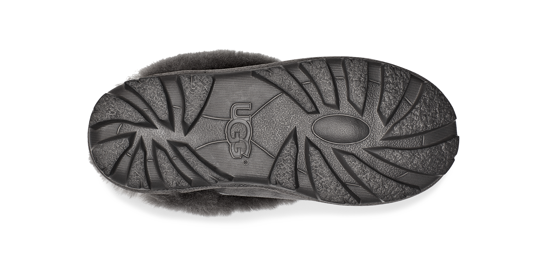 The black rubber outsole of a UGG slipper, showing the brand logo and tread pattern, photographed from a top-down view on a white background.