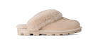 A single slip-on mule slipper in beige suede with a fluffy cream shearling-style strap and matching beige sole, shown in side profile on a white background.