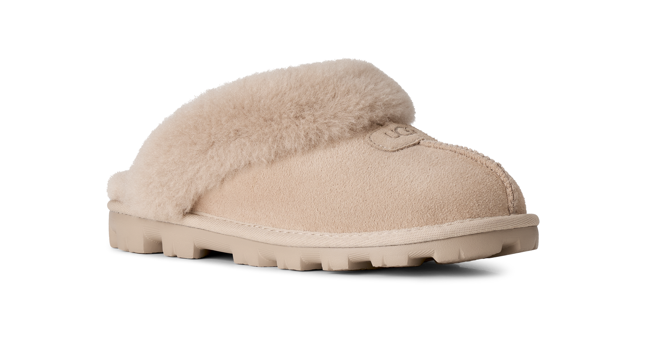 A single beige slip-on slipper with soft shearling-style fur trim and a chunky lug sole, shown on a clean white background.