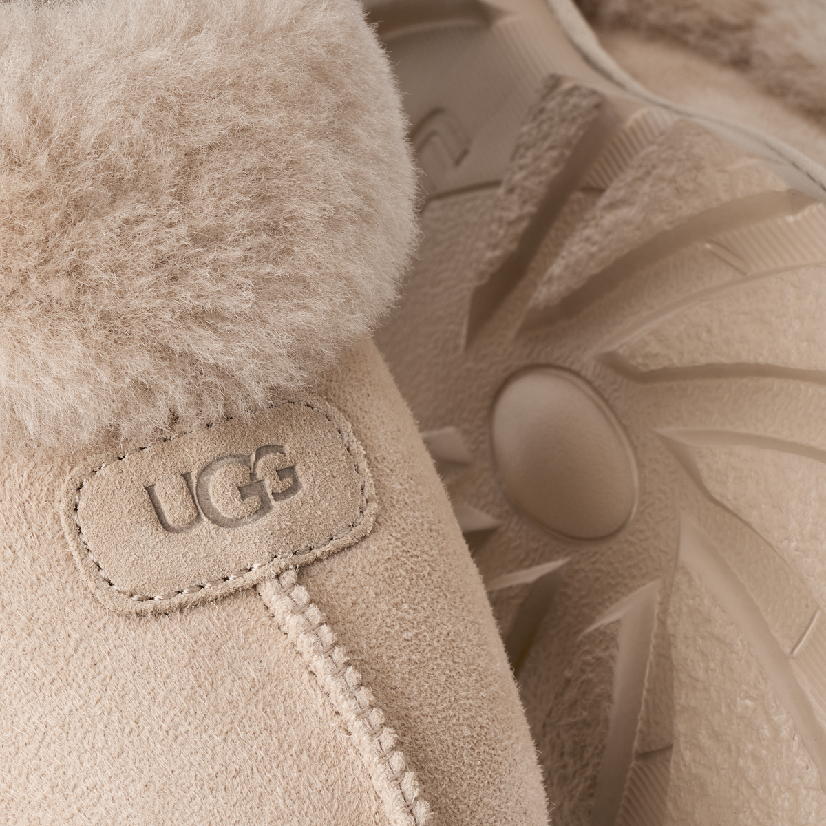 Close-up of a beige UGG boot showing the suede exterior, plush shearling lining, and embossed UGG logo patch.