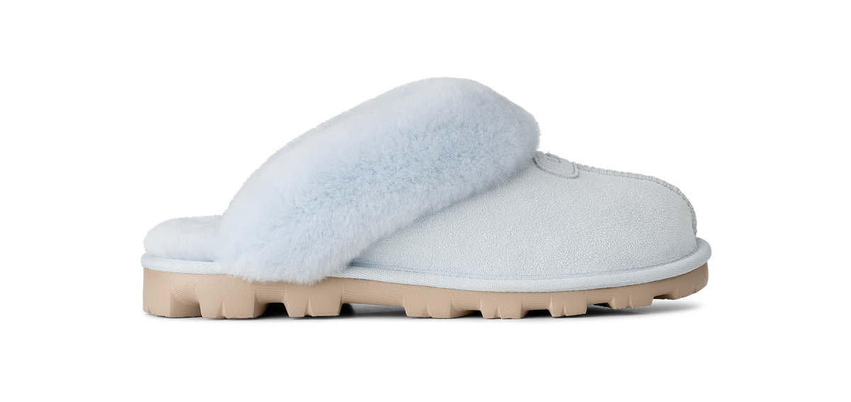 A single light blue slip-on slipper with fluffy faux-fur trim and a chunky beige sole, shown in profile against a solid white background.