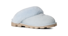 A single light blue slip-on slipper with fluffy pale blue shearling lining and a tan rubber sole, shown from a side profile on a white background.