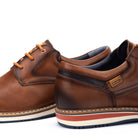 Brown leather shoes with orange laces on a white background