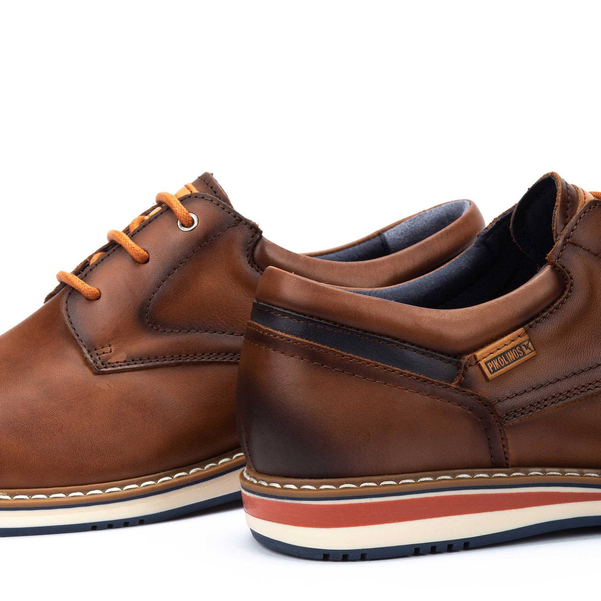 Brown leather shoes with orange laces on a white background