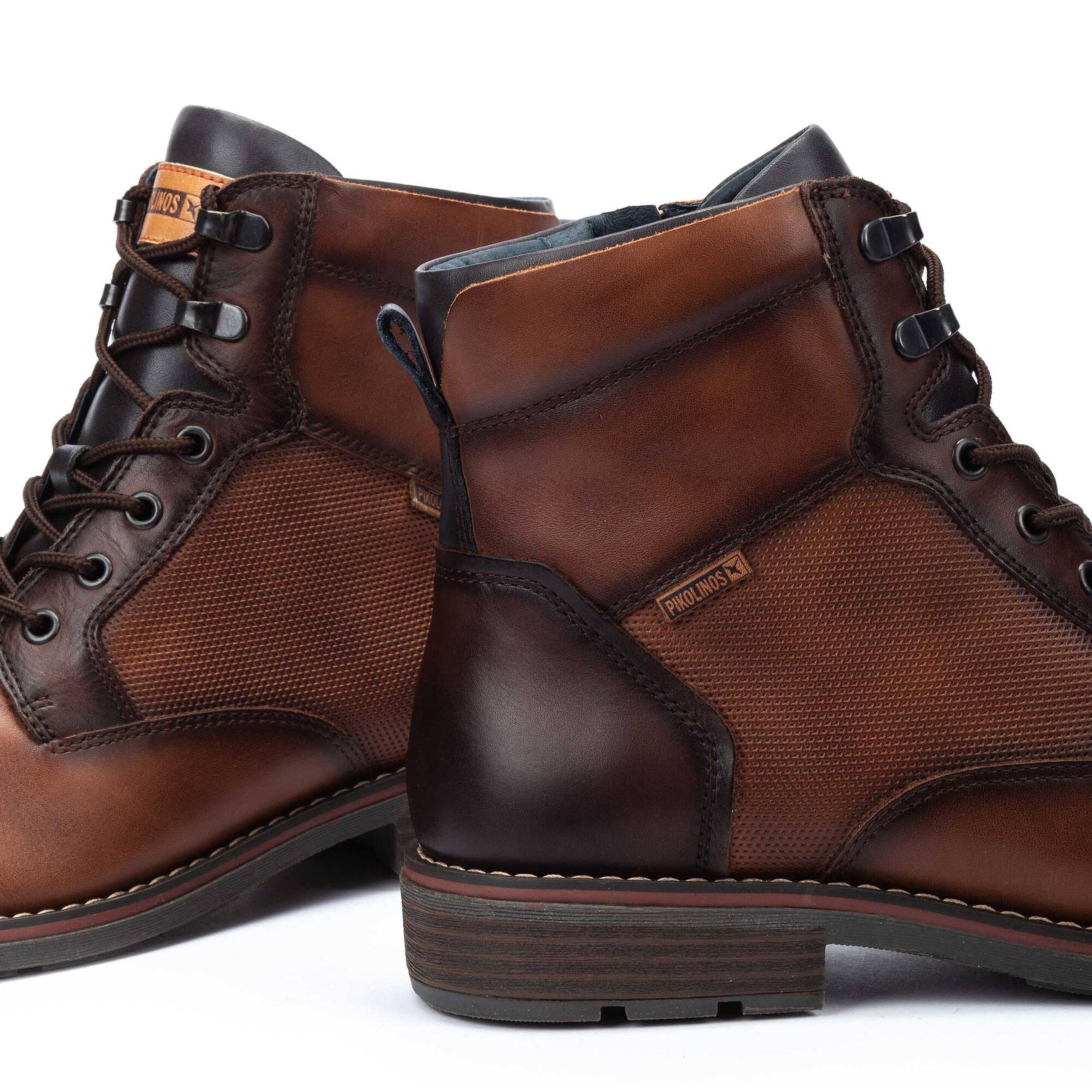 Pair of brown leather boots with visible brand logo on a white background