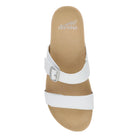 White sandal with a strap and buckle on a beige sole, featuring the Dansko logo.