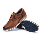 Brown leather shoe with black sole on a white background