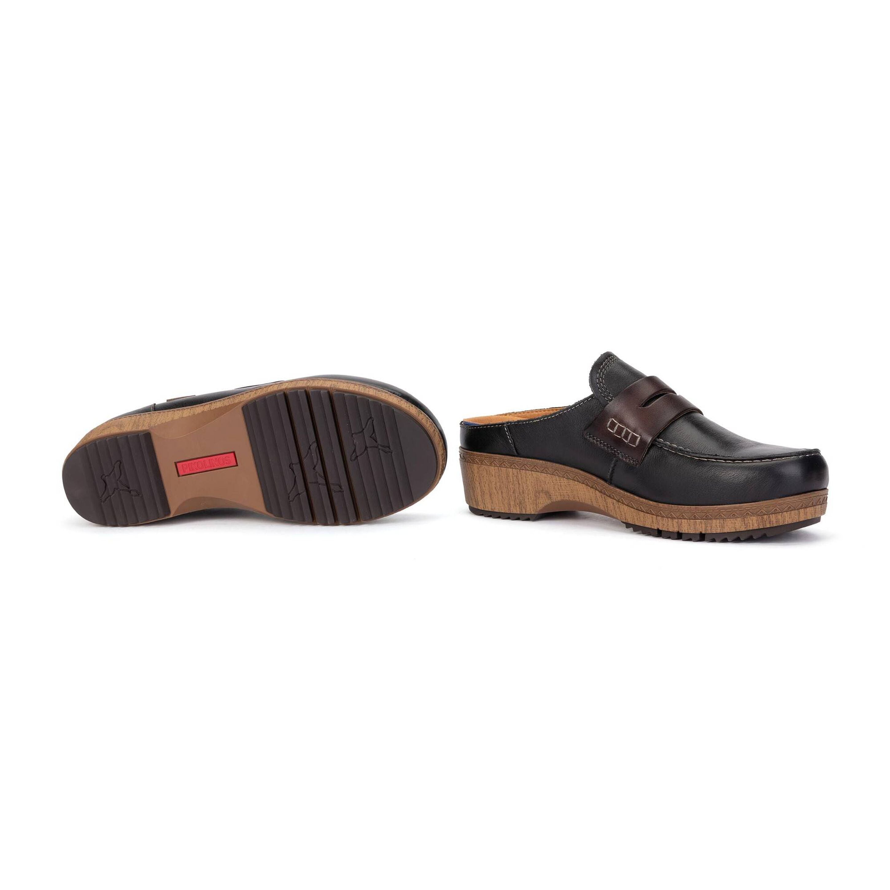 A pair of black leather clogs with brown wedge soles, shown from the side and sole views on a white background.