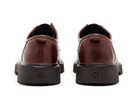 A pair of dark brown leather oxford shoes shown from the back, featuring chunky black platform soles with an embossed 'CI' logo, set against a plain white background.